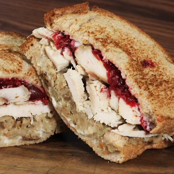A Beantown Pastrami deli sandwich, cut in half, revealing turkey, stuffing, and cranberry sauce.