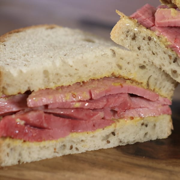 Close-up of a Beantown Pastrami sandwich with thick-cut pastrami and mustard on rye bread.